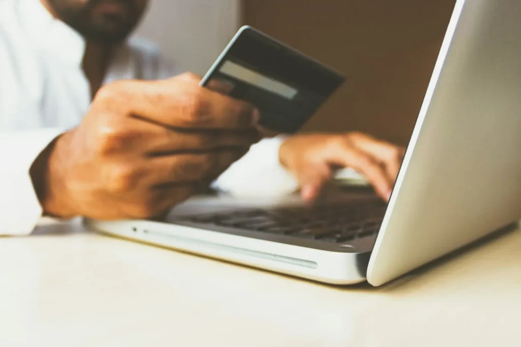 Site vitrine ou site e-commerce : lequel choisir pour votre activité ? — Aurea Media Personne tenant une carte bancaire devant un ordinateur portable pour payer en ligne